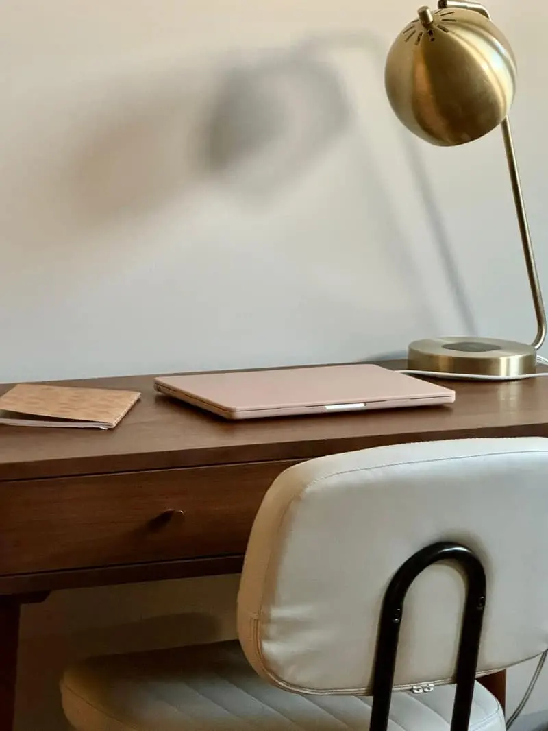 A desk with a closed notebook, a laptop a clean space for working on goals with a busy schedule