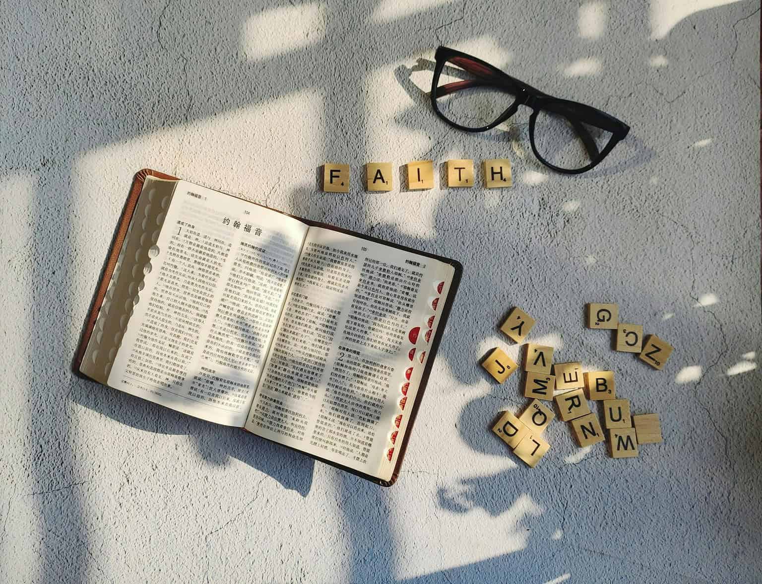 A book and glasses on a table with the word faith